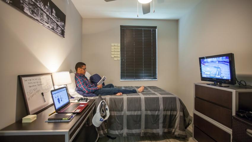 Male student studying on bed in residence hall